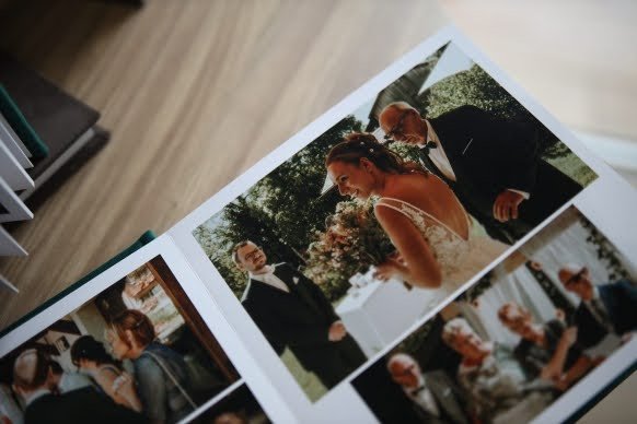 A close-up of a wedding photo album with multiple images of a ceremony. The album pages show guests and the bride and groom exchanging vows.