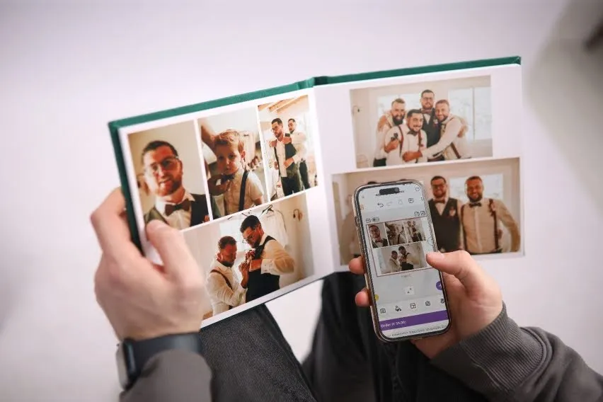 A person holding a wedding photo album and a phone, both showing pictures of groomsmen and family moments.