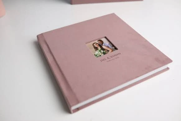 A pink wedding photo album with a small cover photo of the couple and their names, Jael & Shawn, along with the wedding date.
